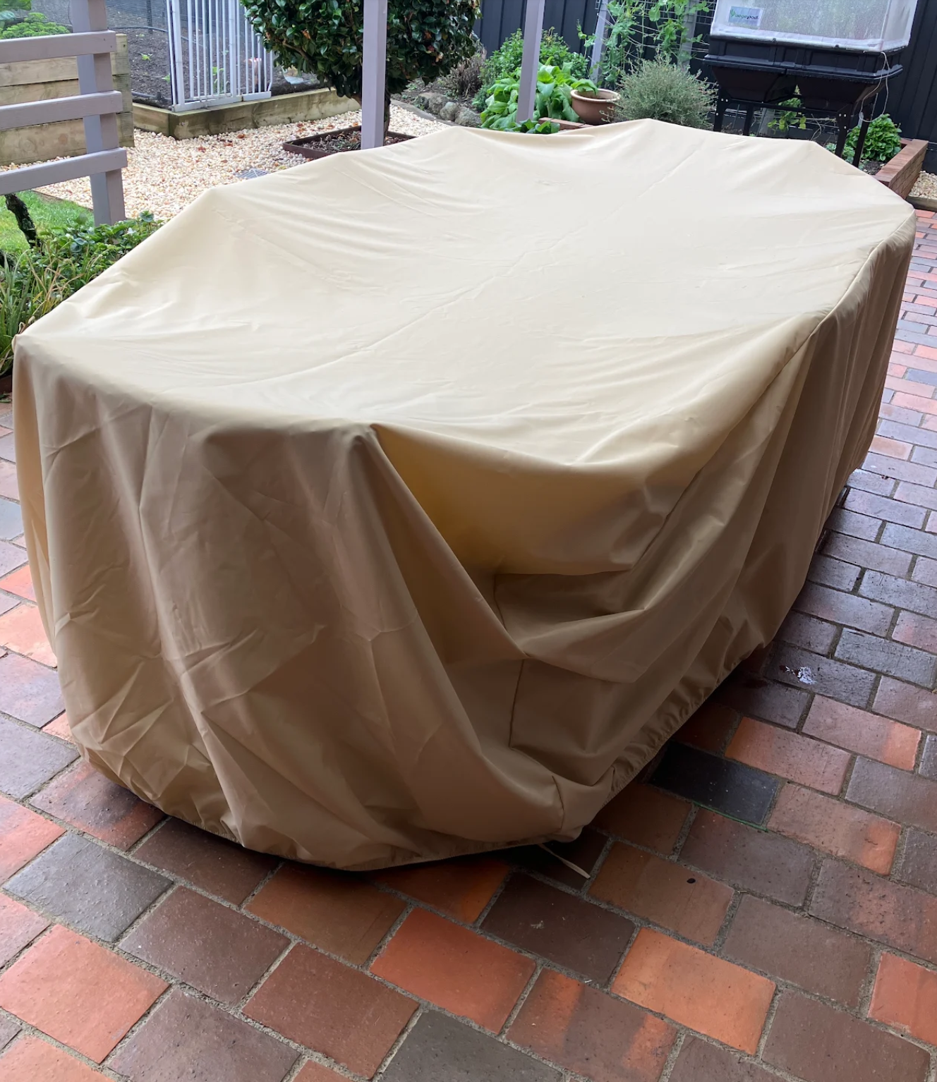 Custom made patio set cover in beige fitted over a patio dining set on a brick patio – The Cover Company USA