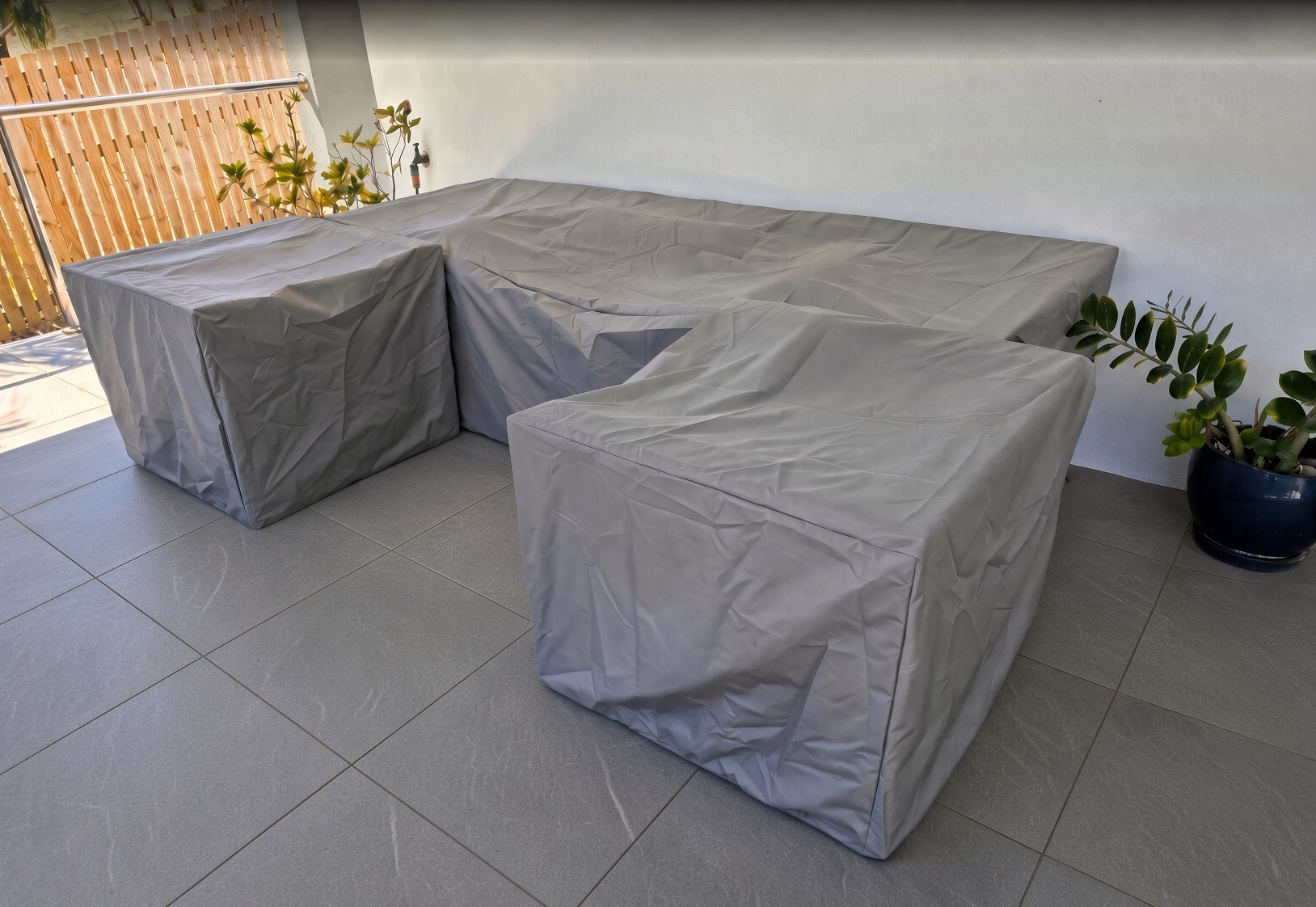 Custom made patio sofa cover in gray with matching chair covers on a tiled patio – The Cover Company USA